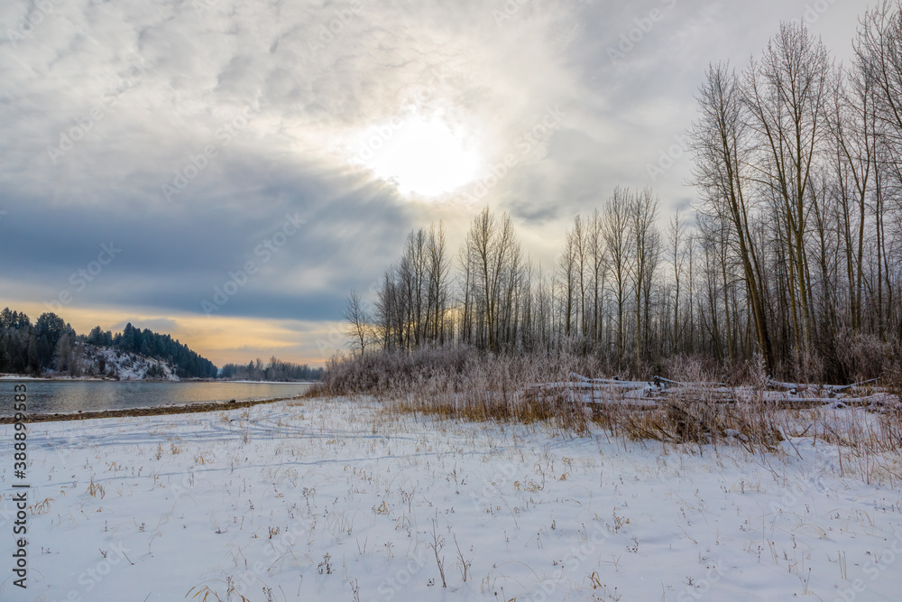 cold early morning with sun blazing in a cloudy sky in mid-winter along the Flathead River, northwestern Montana cold early morning with sun blazing in a cloudy sky in mid-winter along the Flathead River, northwestern Montana