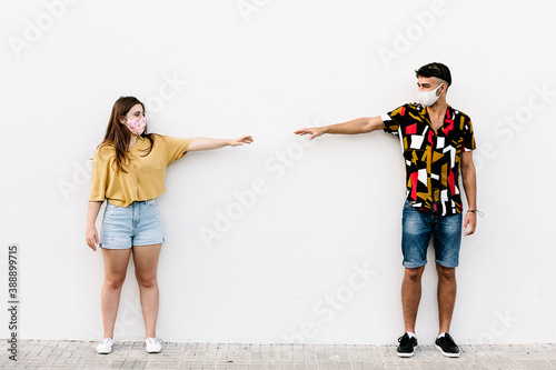 Young friends keeping social distancing while standing against wall photo