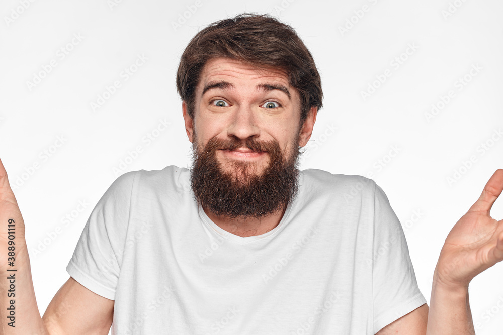 cheerful bearded man in a white t-shirt emotions gestures with his hands light background studio cheerful bearded man in a white t-shirt emotions gestures with his hands light background studio