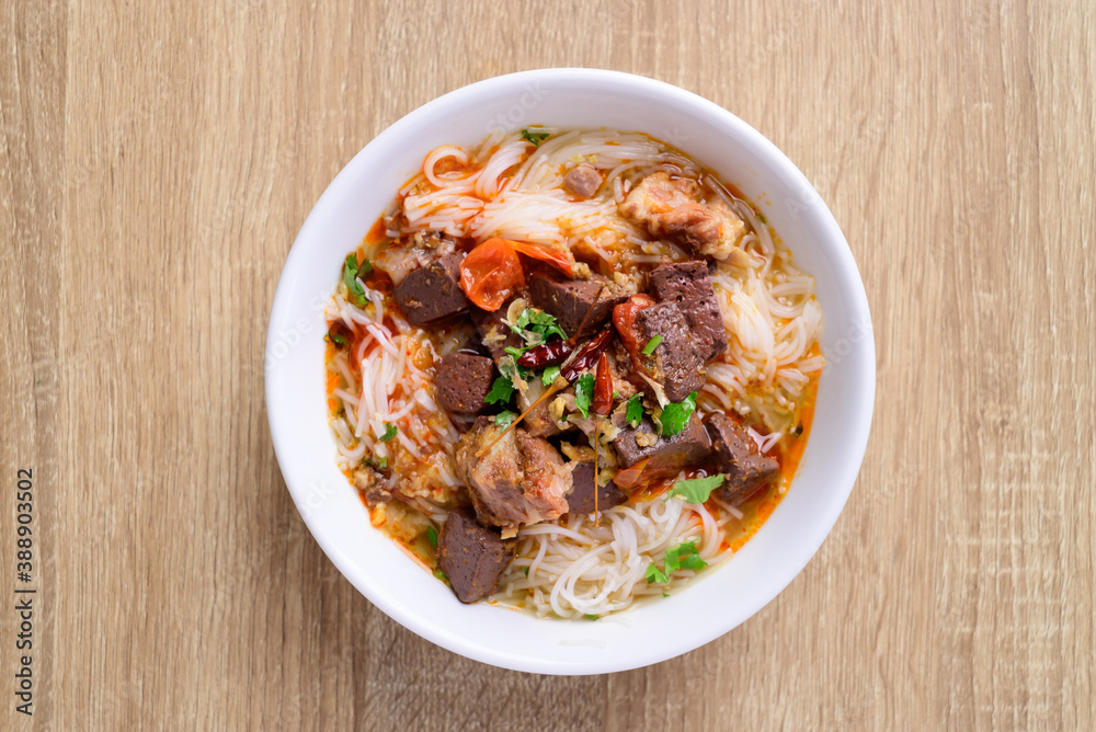 Northern Thai food (Kanom Jeen Nam Ngeaw), Rice noodles spicy soup with pork and pork blood in a bowl on wooden background, Top view