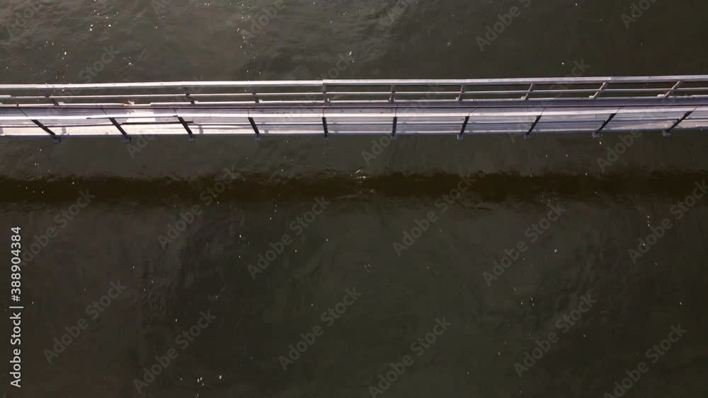 View from above. Part of a wooden suspension bridge against the background of a wide river. View from above. Part of a wooden suspension bridge against the background of a wide river.