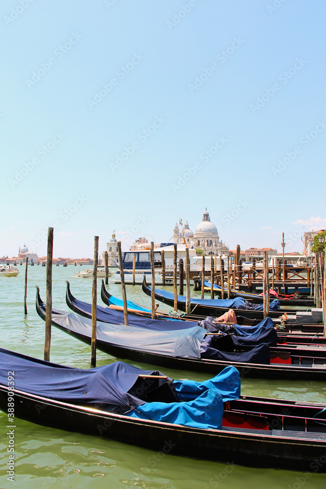 Gondola boats lined up in Venice, Italy with dome in background. No people, space for copy.