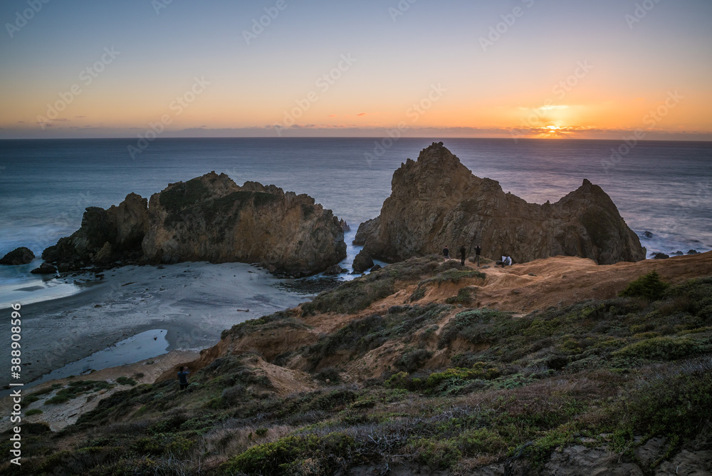 Long exposure image of people watching the sunset in the famous Pfeiffer Beach and the Keyhole Arch.