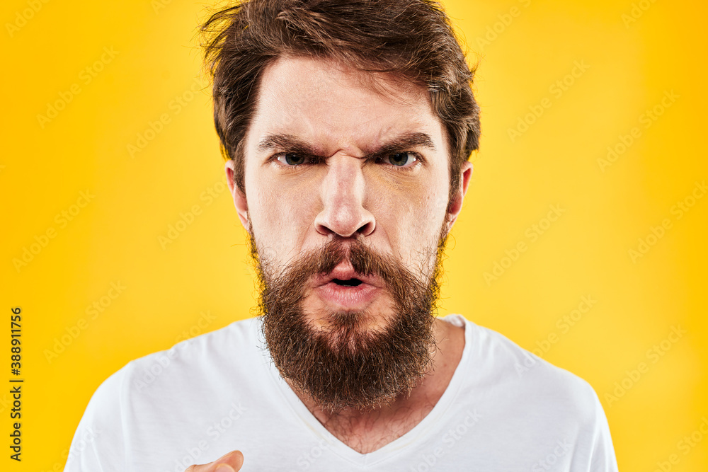 Obraz premium emotional bearded man gesturing with hands aggression discontent close-up yellow background