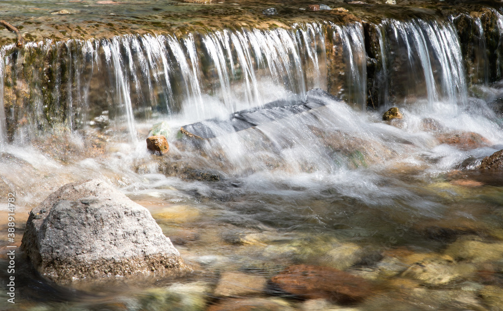 Obraz premium Small waterfall flowing in the summer mountain