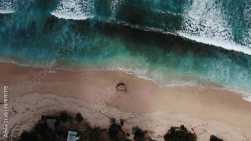 Aerial view of waves rolling one by one to the Nunggalan Beach, Uluwatu, Bali, Indonesia | Bali, South Kuta top view of the picturesque wrecked ship. Shadow from the clouds moves slowly photo