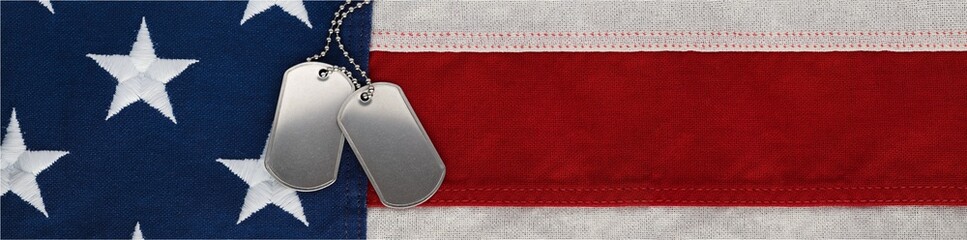 US military soldier's dog tags, rough and worn with blank space for text, on the American flag. Memorial Day or Veterans Day concept.