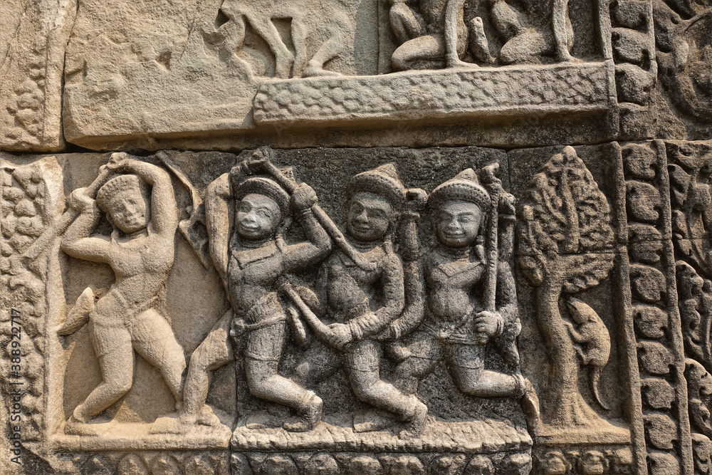 Ancient bas-relief on the wall of the famous Angkor temple. Figures of people, animals, wood are carved on the stone. Ornament around the perimeter. Unesco heritage. Cambodia. Ancient bas-relief on the wall of the famous Angkor temple. Figures of people, animals, wood are carved on the stone. Ornament around the perimeter. Unesco heritage. Cambodia.