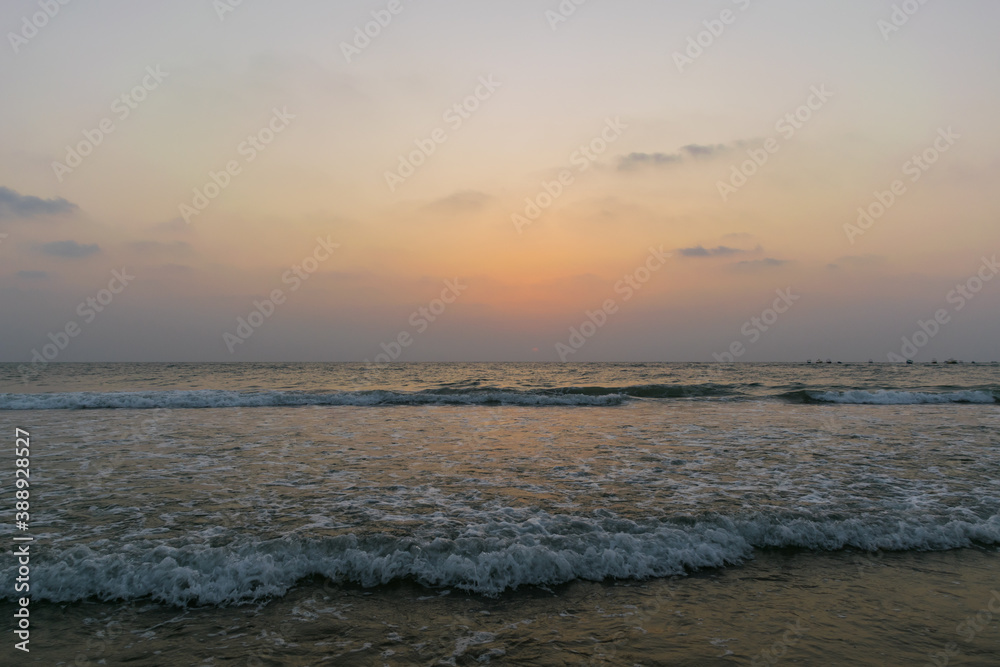 Beautiful view of sea waves flowing into sand at Baga beach in Goa, India