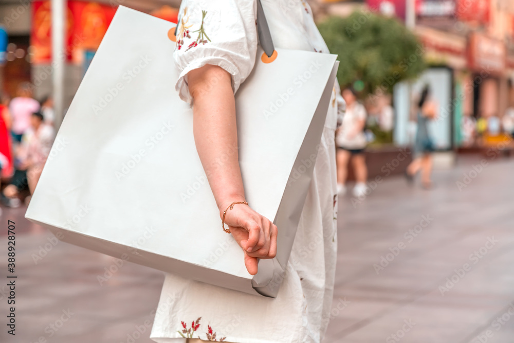 After day shopping. Close-up of young woman carrying shopping bags while walking along the street