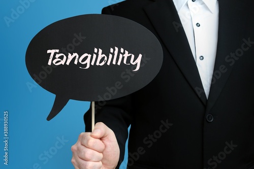 Tangibility. Businessman holds speech bubble in his hand. Handwritten Word/Text on sign.