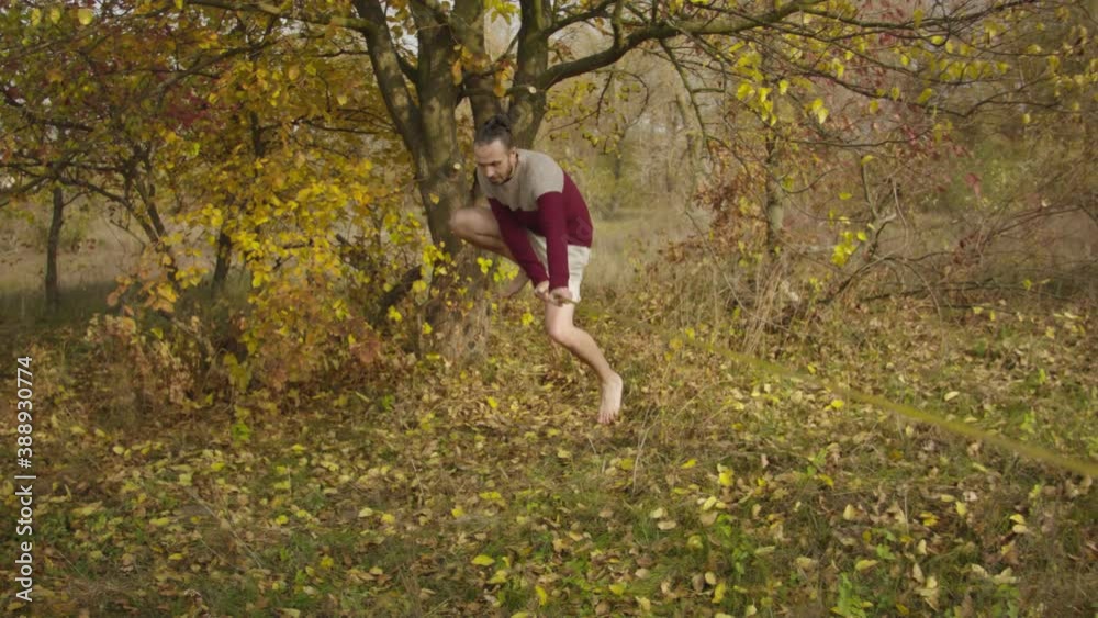 Caucasian man practicing slackline in the autumn forest. A man practices highlining in the autumn forest at dawn. Caucasian man practicing slackline in the autumn forest. A man practices highlining in the autumn forest at dawn.