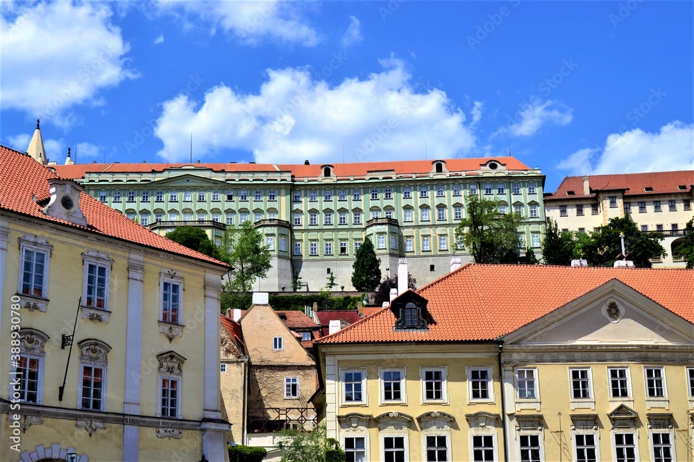 Prague and Czech Republic during sunny day. Ancient church and colorful houses in front of the church with blue and white sky background.