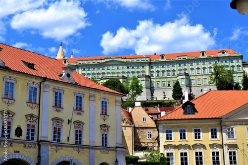 Prague and Czech Republic during sunny day. Ancient church and colorful houses in front of the church with blue and white sky background.