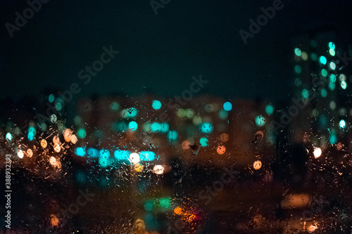 Colorful city lights behind rainy window glass. Bokeh. Bacground.