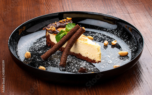 Cheesecake with nuts and chocolate tubes. On a decorative plate