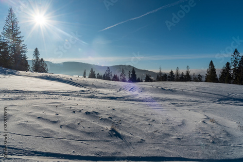 Winter mountain scenery with snow, trees, hills on the background and clear sky wih sun on Cienkow mountain ridge in Beskid Slaski mountains in Poland photo