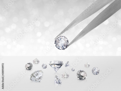 Diamond in tweezers on white shining bokeh background. concept for chossing best diamond gem design photo