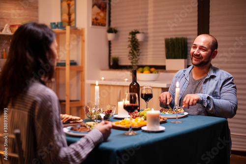 Lovers enjoying tasty food while having dinner in kitchen. Relax happy people  sitting at table in kitchen  enjoying the meal  celebrating anniversary in the dining room.