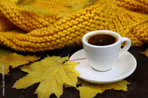 Autumn coffee with yellow leaves on a wooden table background