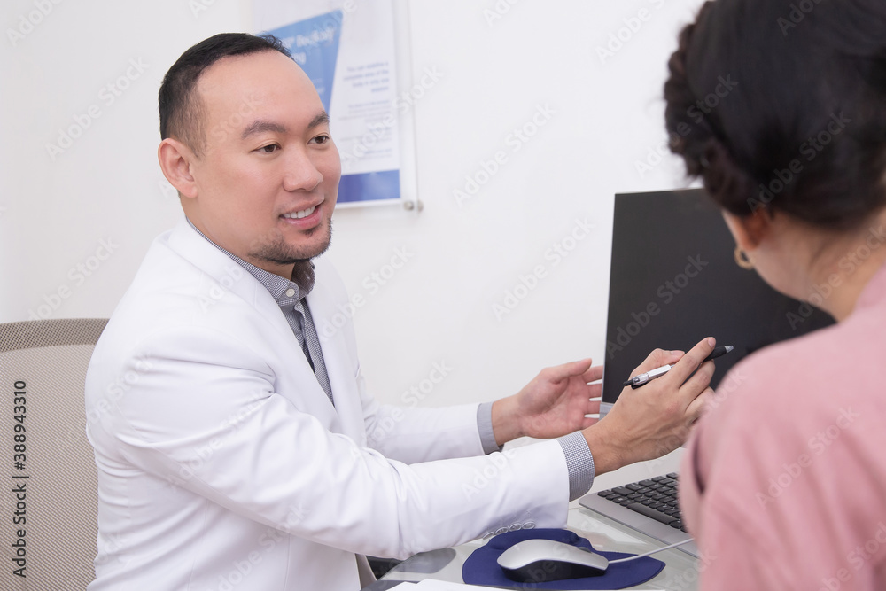 Doctor or professional beautician man consultating patient woman and pointing at computer screen in office or hospital. Healthcare, wellness and medicine