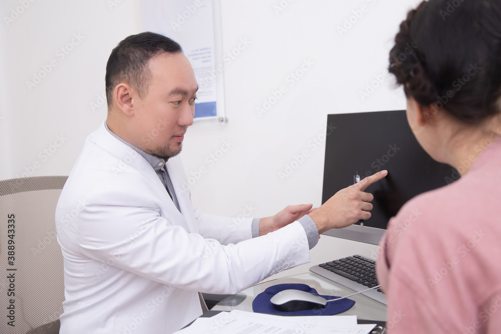 Obraz premium Doctor or professional beautician man consultating patient woman and pointing at computer screen in office or hospital. Healthcare, wellness and medicine