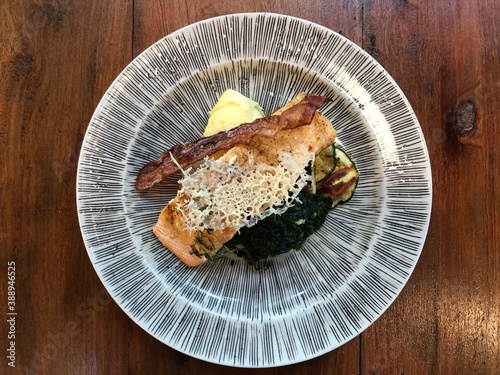 Fried or grilled salmon steaks with vegetables on wooden table.