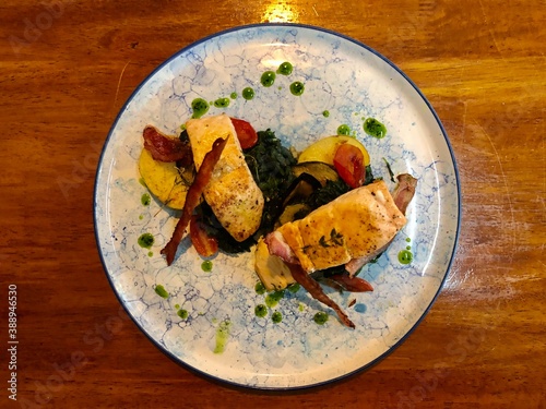 Fried or grilled salmon steaks with vegetables on wooden table.