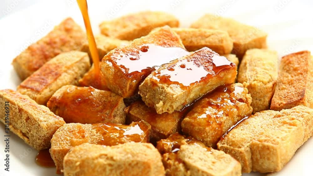 Pouring tamarind sauce on fried tofu in plate , Asian food. Pouring tamarind sauce on fried tofu in plate , Asian food.