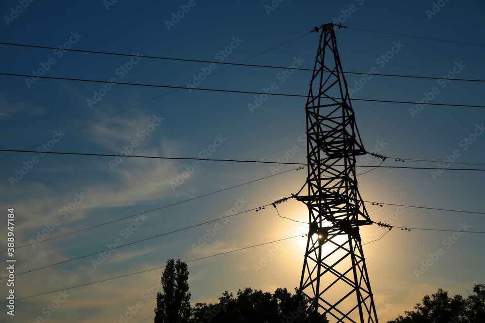 Fototapeta premium Silhouettes of high voltage tower and trees in evening