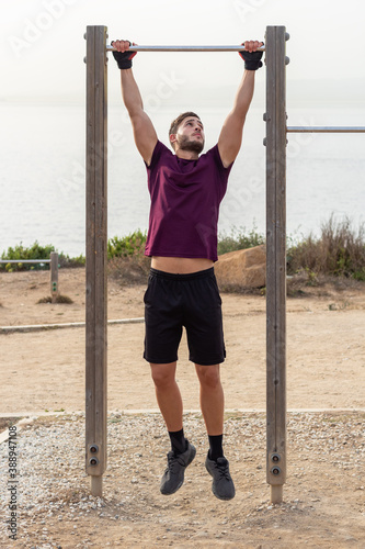 Young man doing pull-up bar outdoor