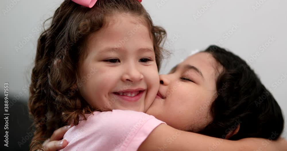 Little girl kissing and hugging sibling sister, family love affection Little girl kissing and hugging sibling sister, family love affection