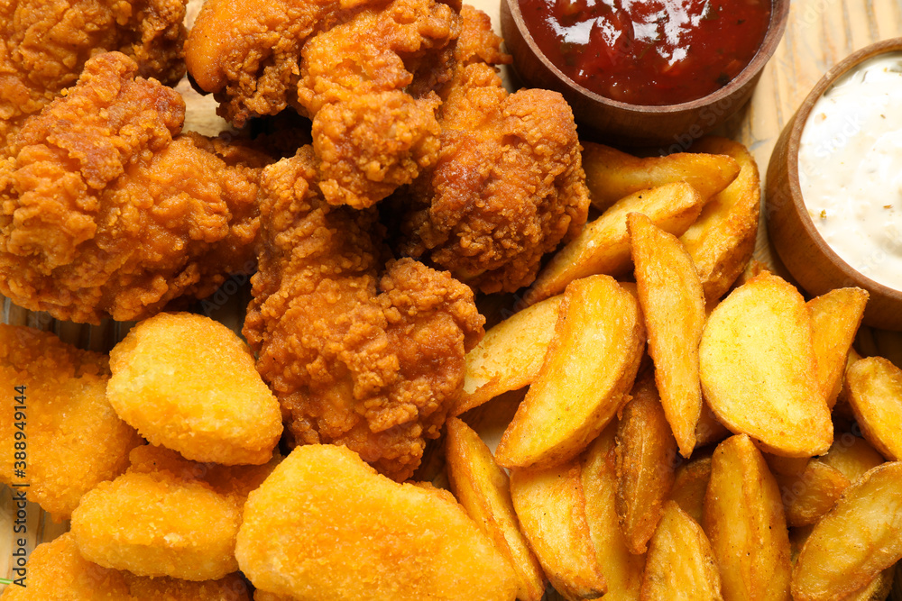 Tasty deep fried chicken pieces and nuggets with garnish as background, top view Tasty deep fried chicken pieces and nuggets with garnish as background, top view