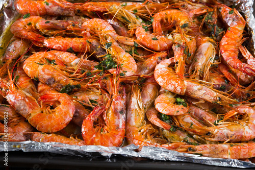 Appetizing baked shrimps with herbs in baking tray with foil