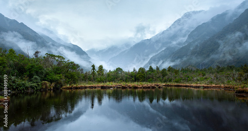 Franz Josef Glacier valley and mountains reflected in Peter's pool in the rain, South Island, New Zealand