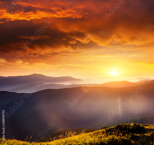 Mystery mountains are illuminated by the sunset. Picture of colorful cloudy sky.