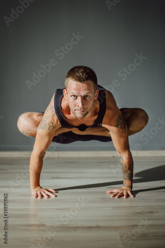 A man stands on his arms with his legs tucked under him. Yoga pose on arms.