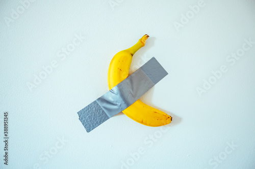 A banana taped to the white wall. photo
