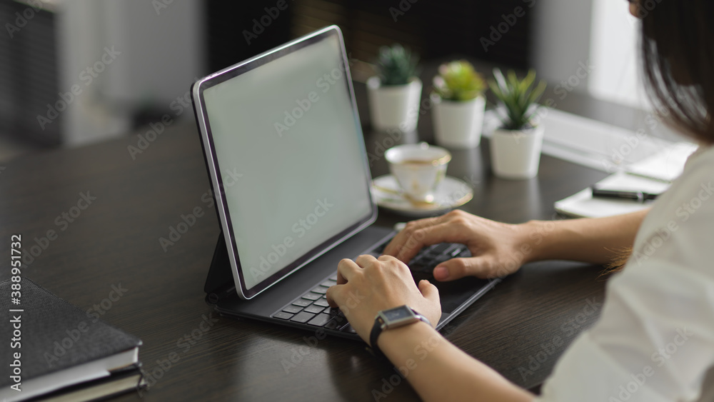 Female office worker typing on laptop computer in modern office room Female office worker typing on laptop computer in modern office room