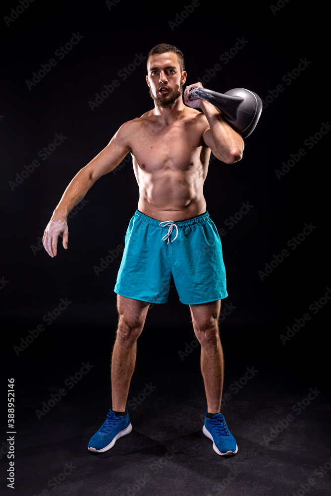 Sporty man doing weight training with kettlebell on a black background. Sporty man doing weight training with kettlebell on a black background.