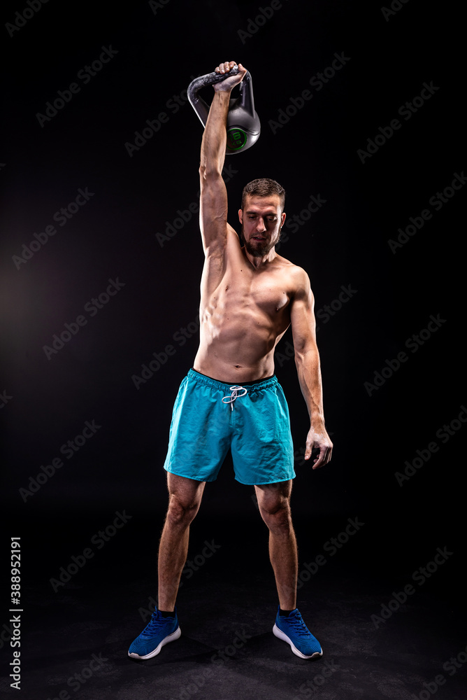 Sporty man doing weight training with kettlebell on a black background.