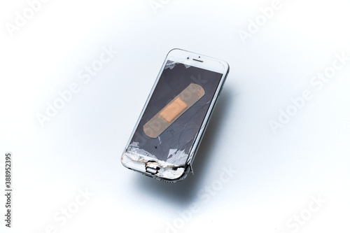 smartphone with broken screen on white background. smartphone to be repaired. mobile phone destroyed. mobile phone fell to the ground. broken mobile phone with patch on the screen. concept