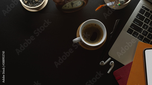 Workspace with laptop, coffee cup, accessories and copy space on black table