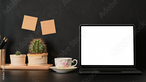 Workspace with laptop, coffee cup, plant pot and sticky-note on the wall, clipping path