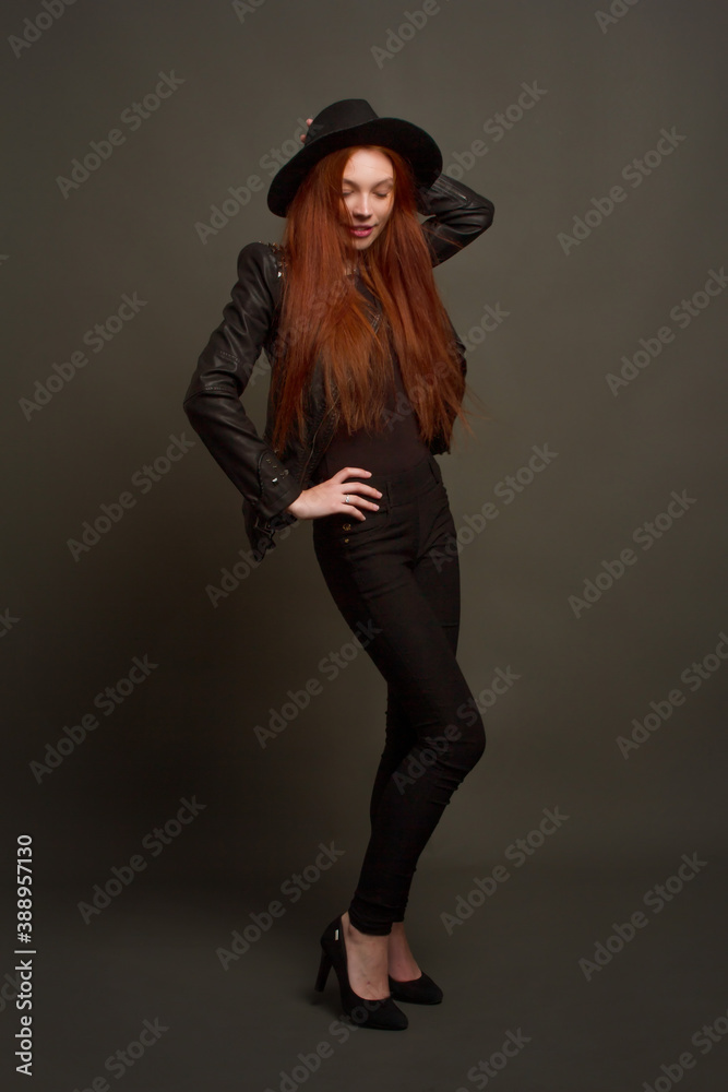 portrait of a young red-haired woman in a black dress. Studio photo on a black background. portrait of a young red-haired woman in a black dress. Studio photo on a black background.
