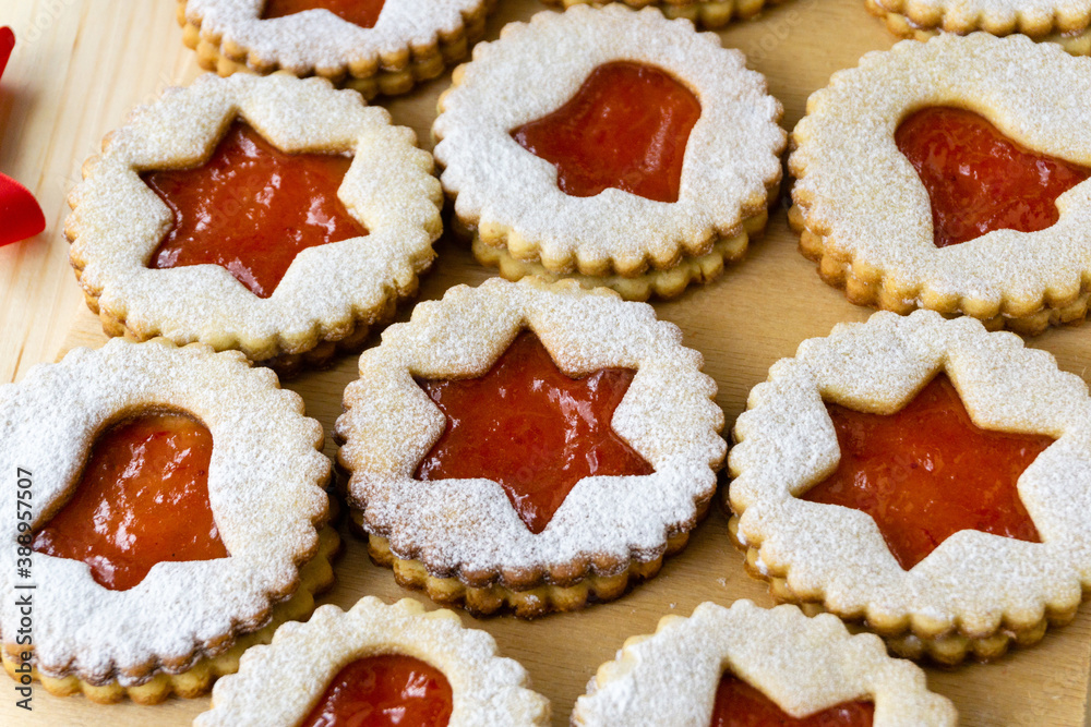 Christmas or new year linzer cookies in the shape of stars and bells with jam on a wooden background