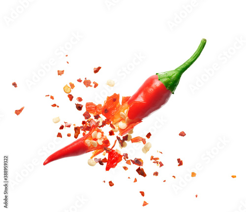 Print op canvas Chili flakes bursting out from red chili pepper over white background