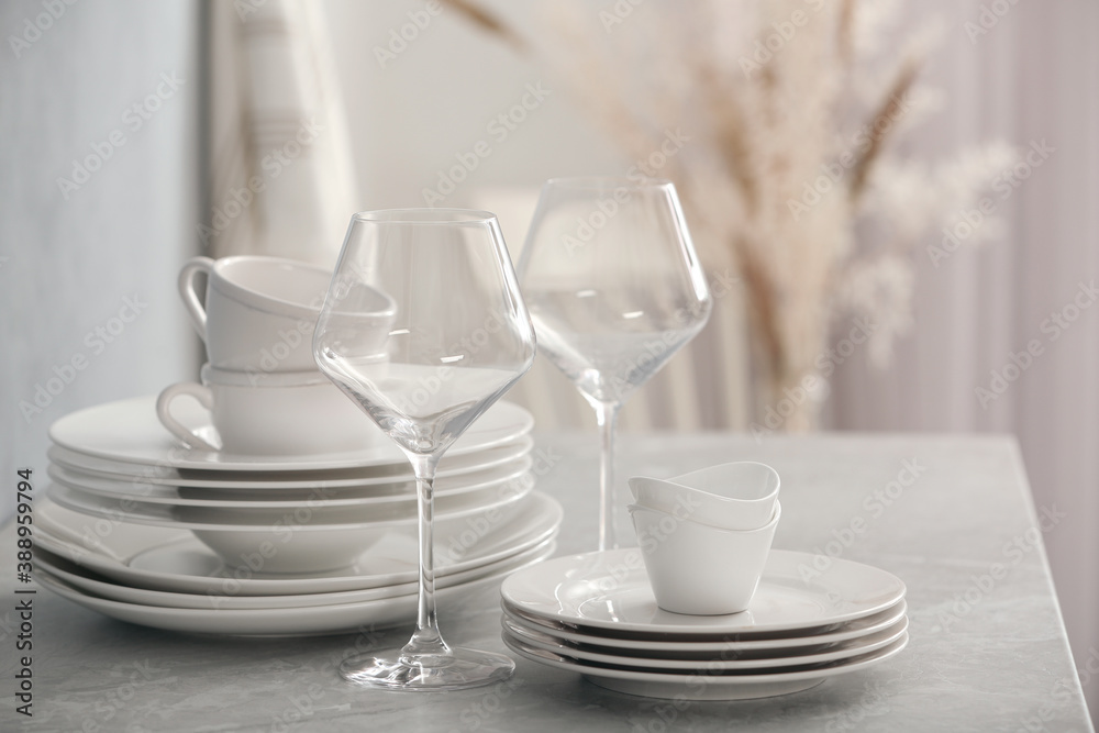 Set of clean dishware and wineglasses on grey table indoors