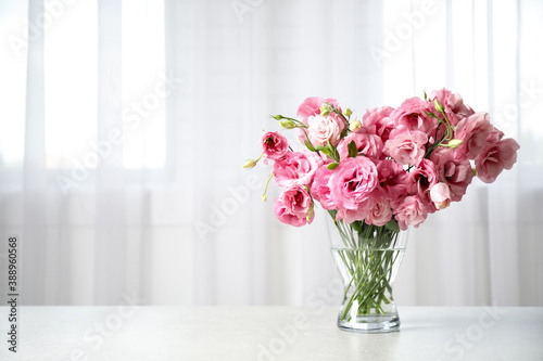 Beautiful pink Eustoma flowers in vase on table indoors. Space for text