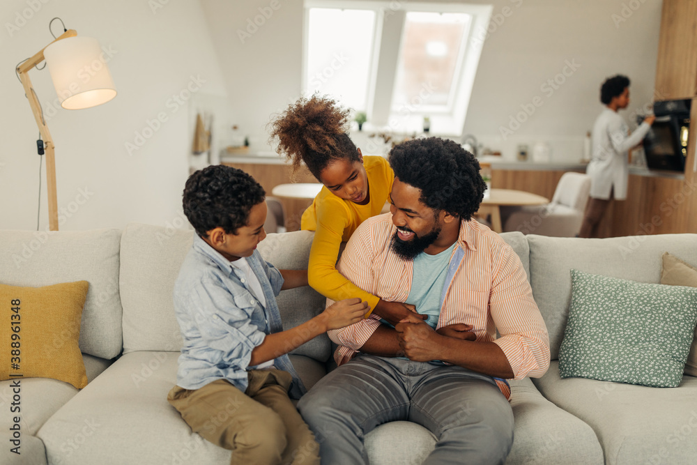 Afro father and his children bonding at home. They are laughing and tickling together Afro father and his children bonding at home. They are laughing and tickling together